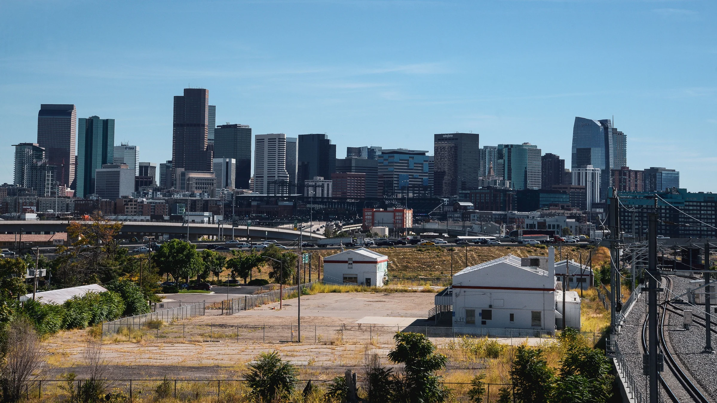 Downtown Denver skyline beyond a rail yard under a clear blue sky