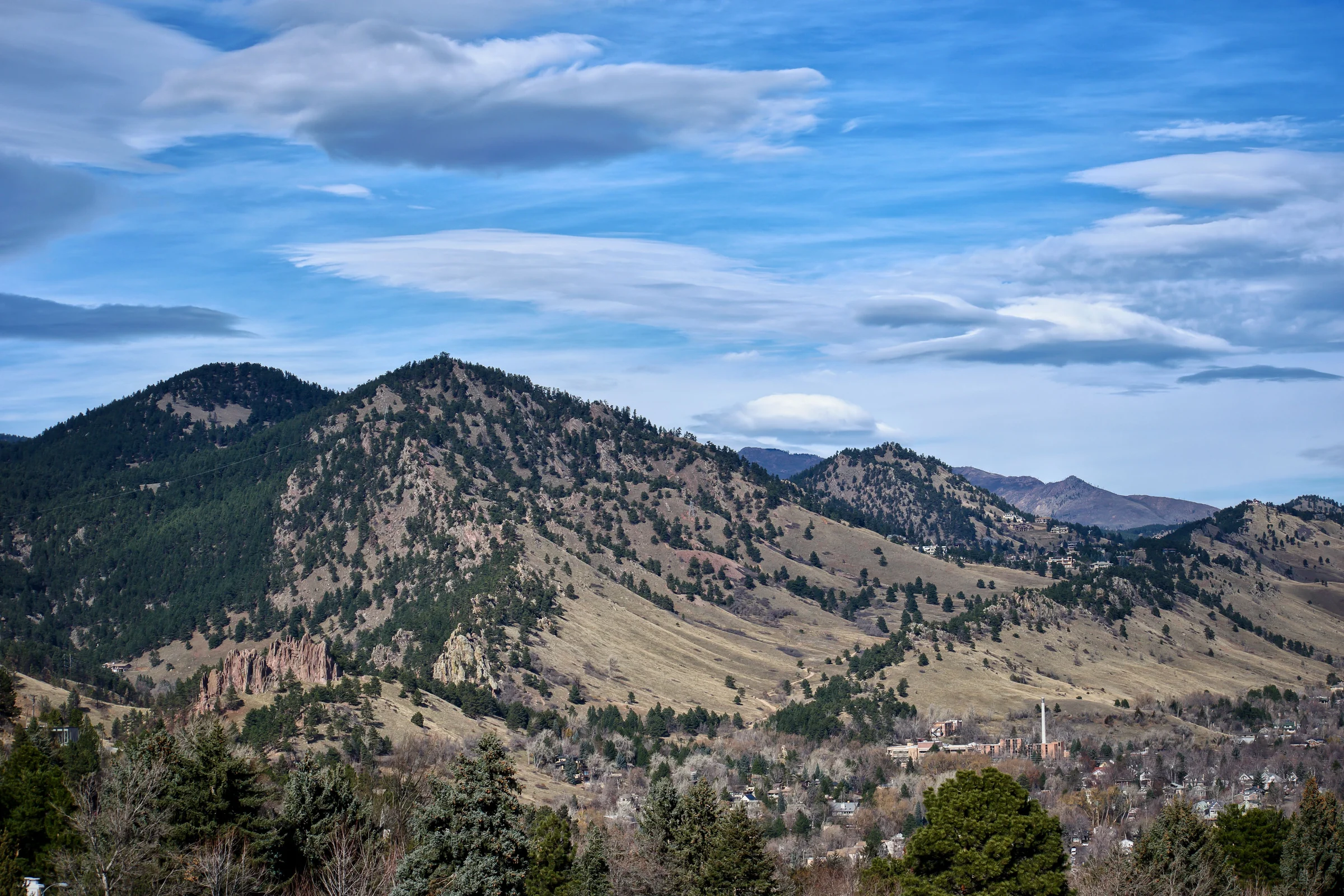 Foothills rising above a Boulder County town under a wide blue sky